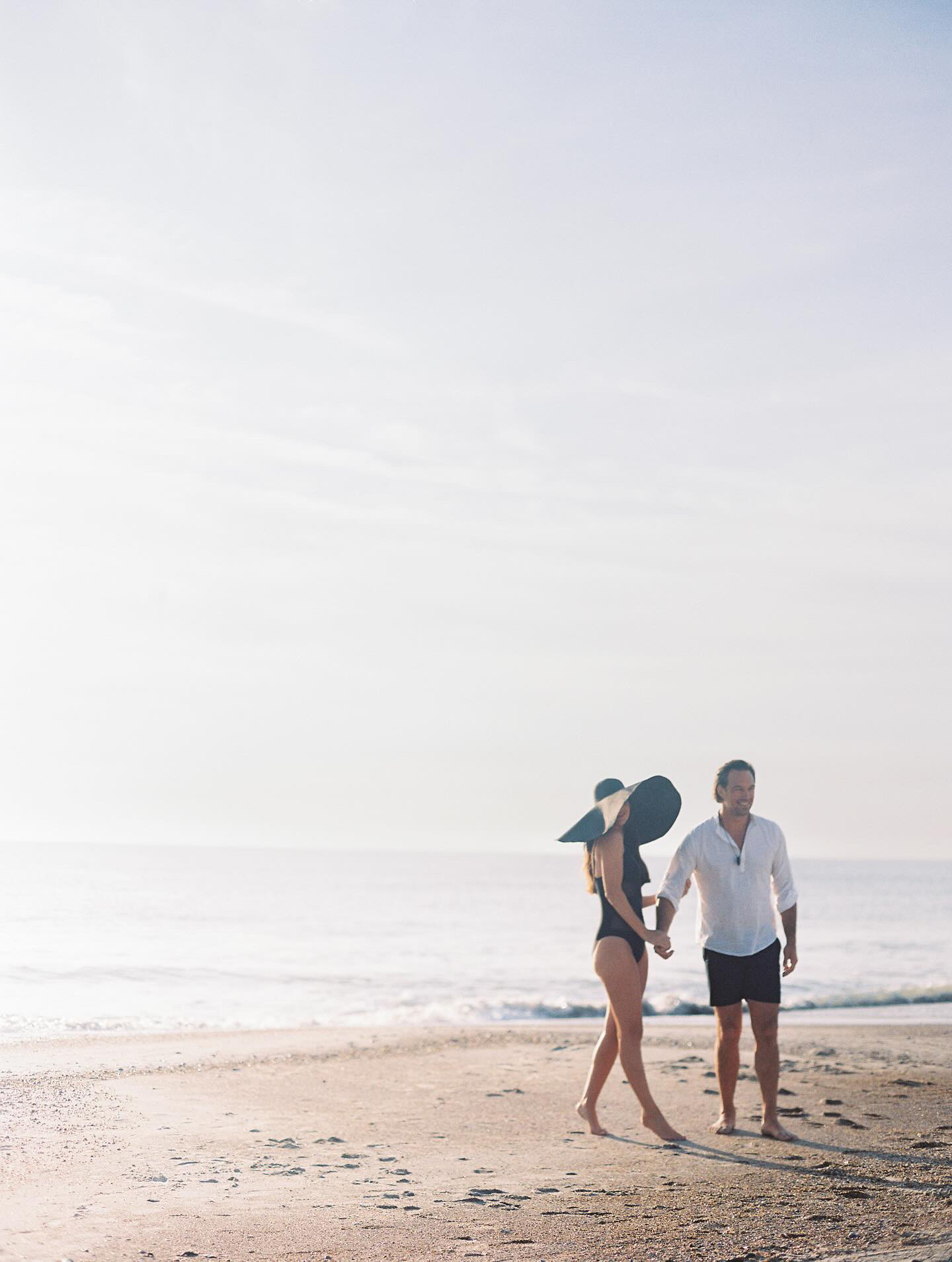 A couple standing on Amelia Island posing for an early morning photoshoot while on their honeymoon. The photo was captured by Kiley Ann Photography.