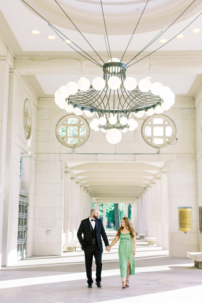 A couple dressed in formal attire posing at the Muny in St. Louis while Kiley Ann Photography captures them walking.