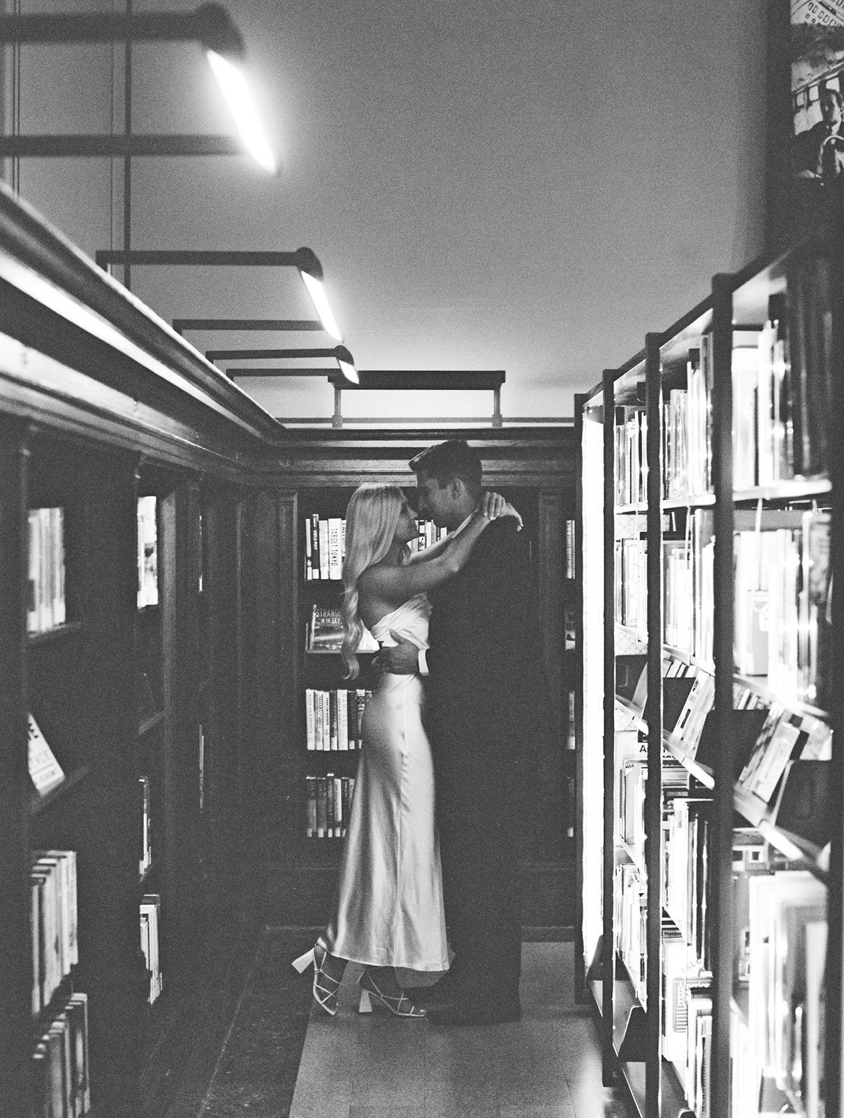 A grainy black and white image captured on 120 mm film in a library during their engagement session.