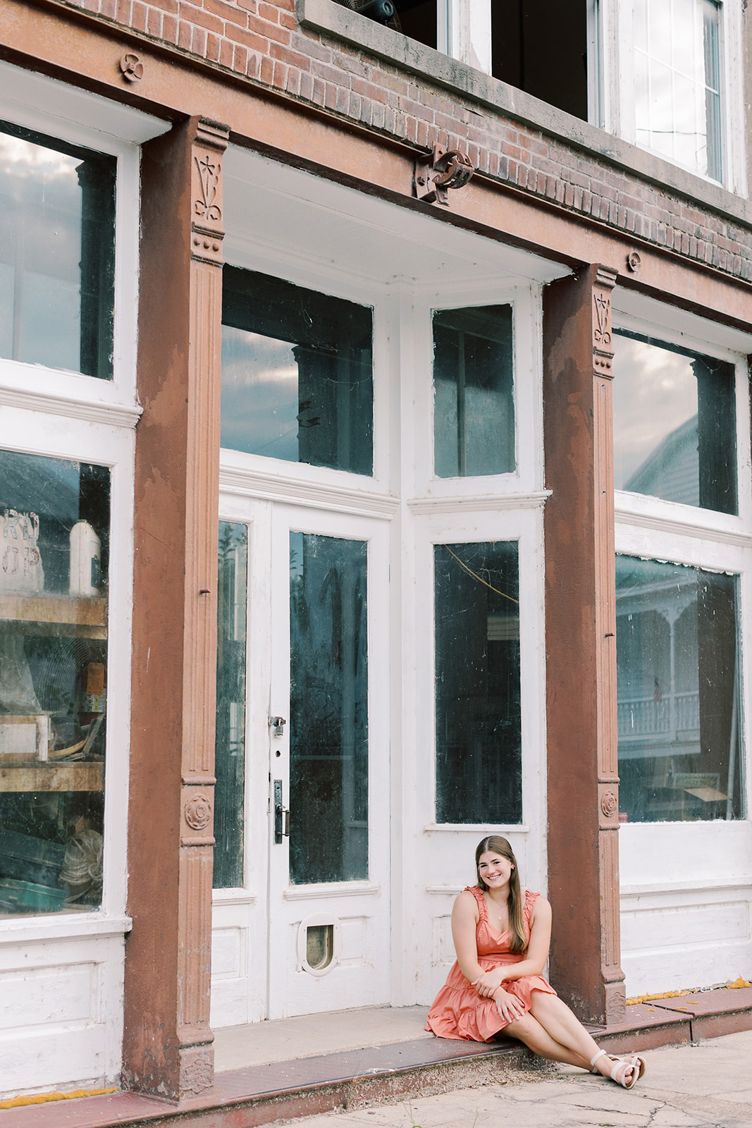 A high school senior posing for her summer senior session in Columbia, Missouri. The photographer, Kiley Ann Photography, captured this female senior in front of a vintage storefront in Mid-Missouri.