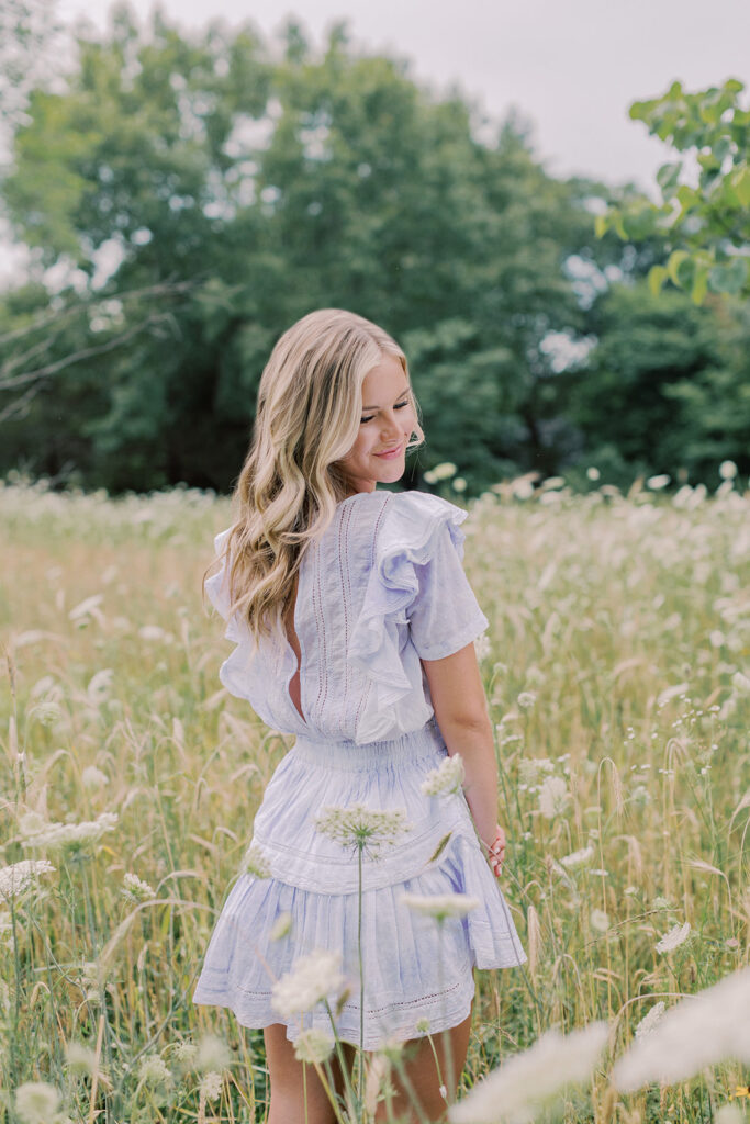 A blonde senior in high school posing in a wildflower field posing for her senior session with Kiley Ann Photography based in Columbia, Missouri.