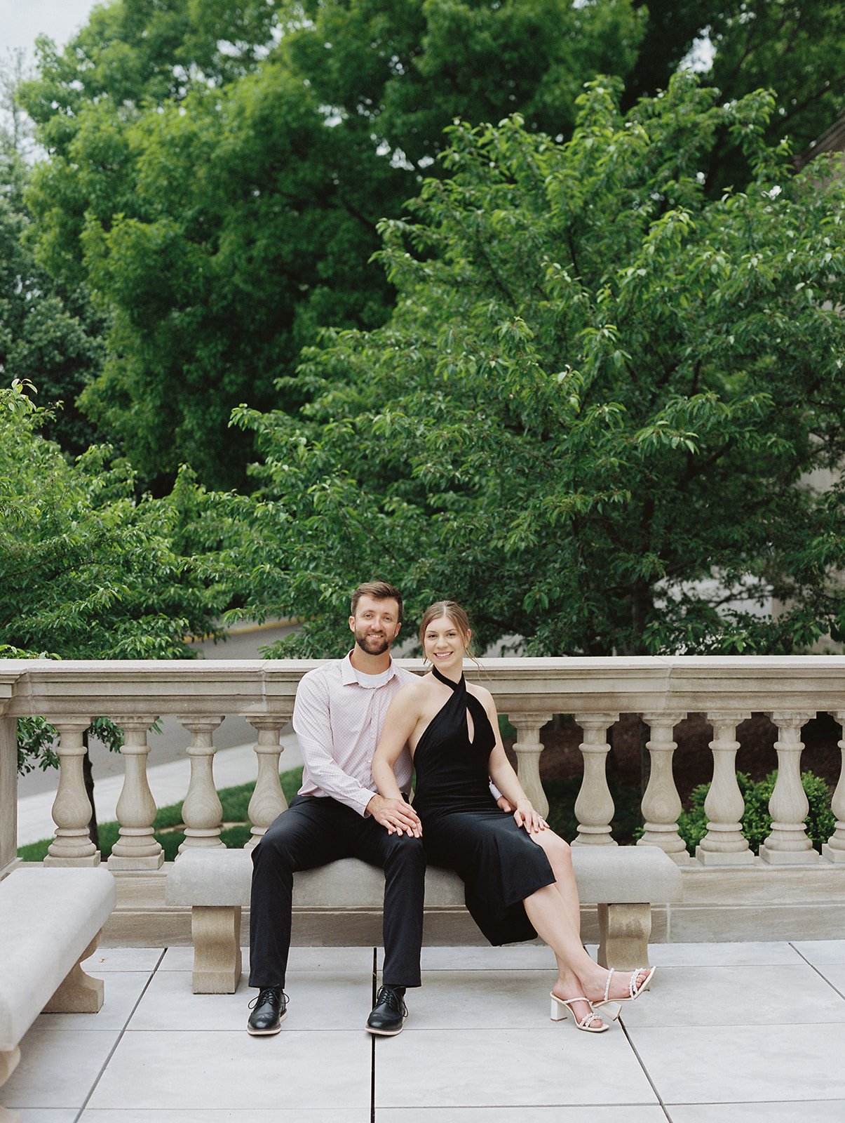 A couple sitting at a bench with green trees in the background at the Missouri Capitol