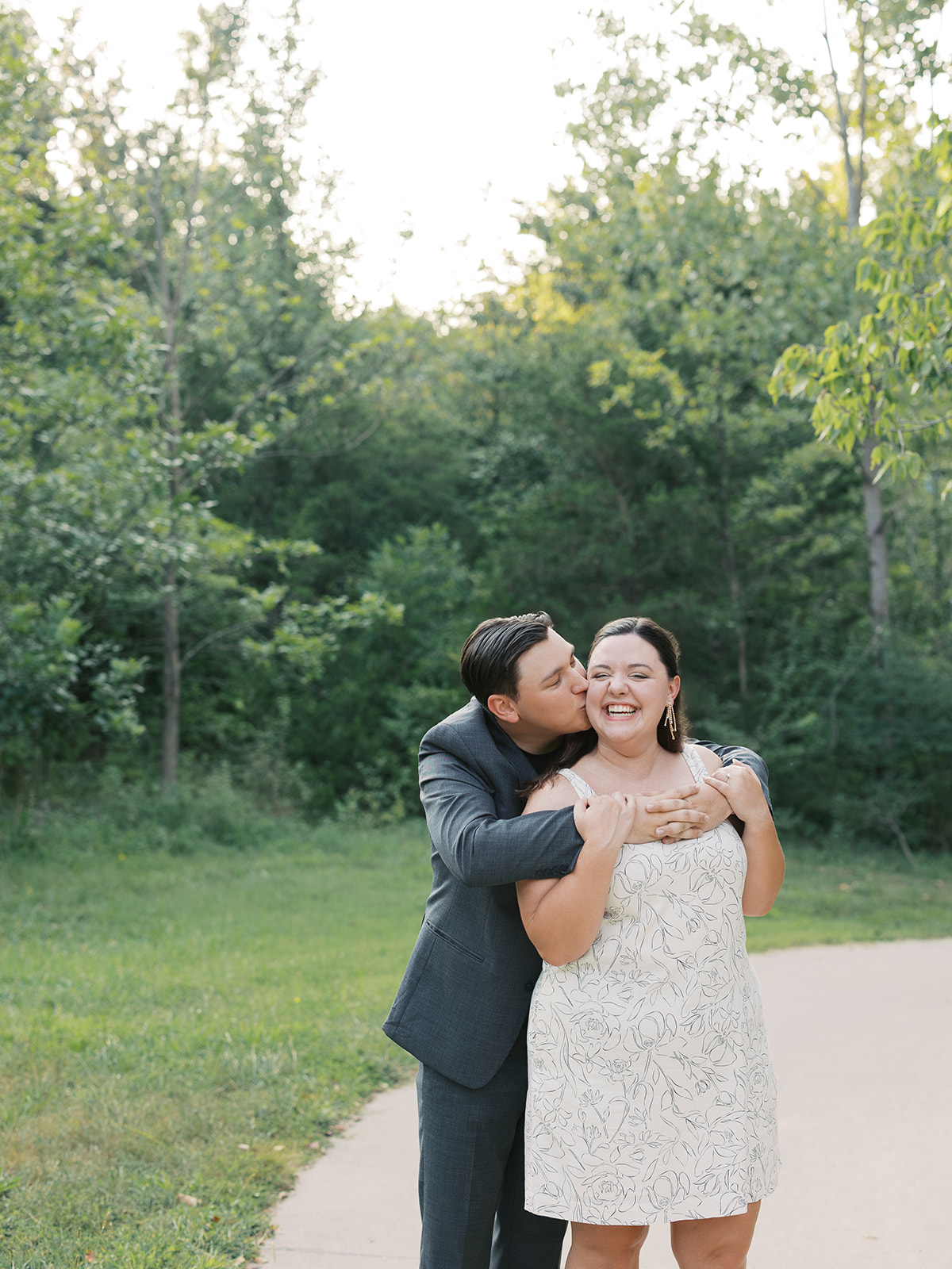 A couple standing in Capen Park posing for their enagement session with Kiley Ann Photography.